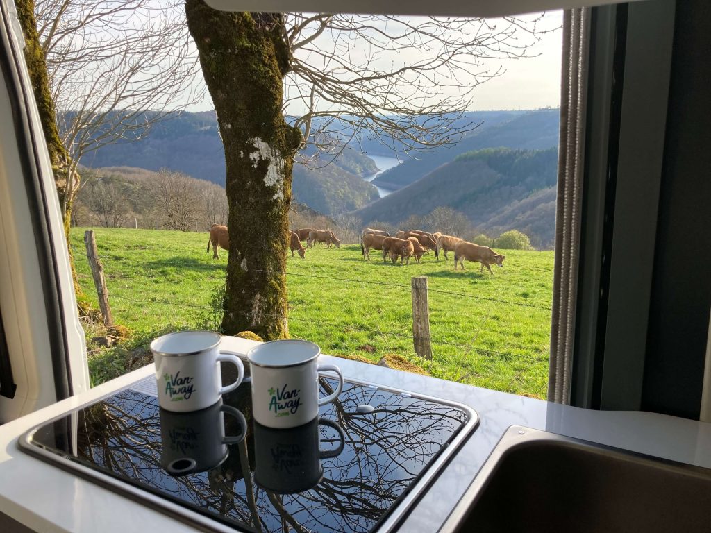 Pause café devant un van aménagé sur un spot nature en montagne